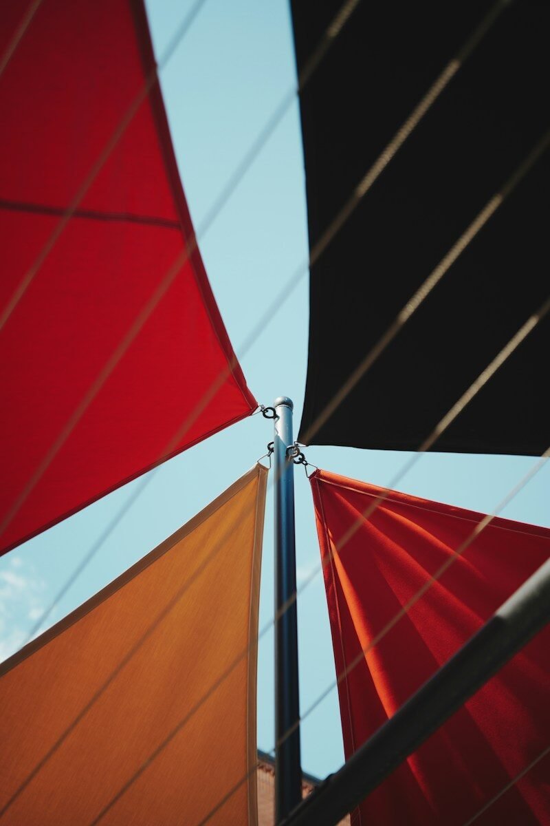 Colorful triangular shade sails against a clear blue sky