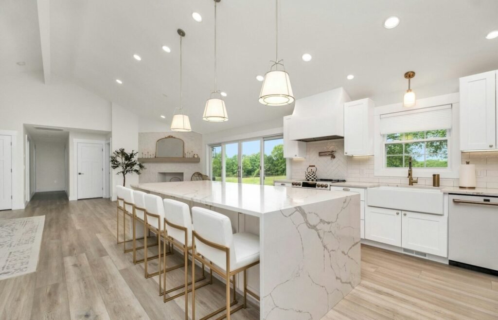 a large kitchen with a marble island and white cabinets