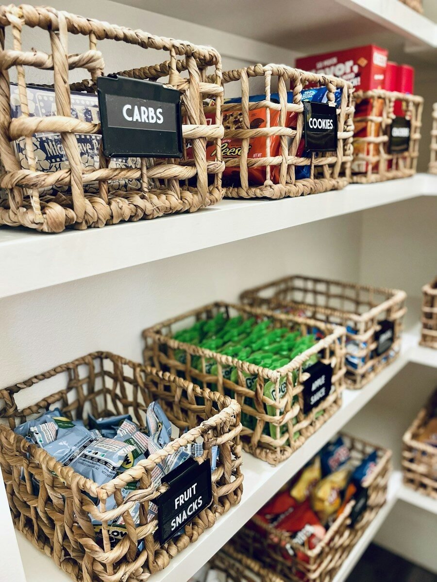 Woven baskets with labels on white pantry shelves
